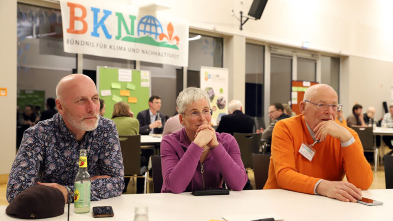 Drei Menschen sitzen an einem Tisch.